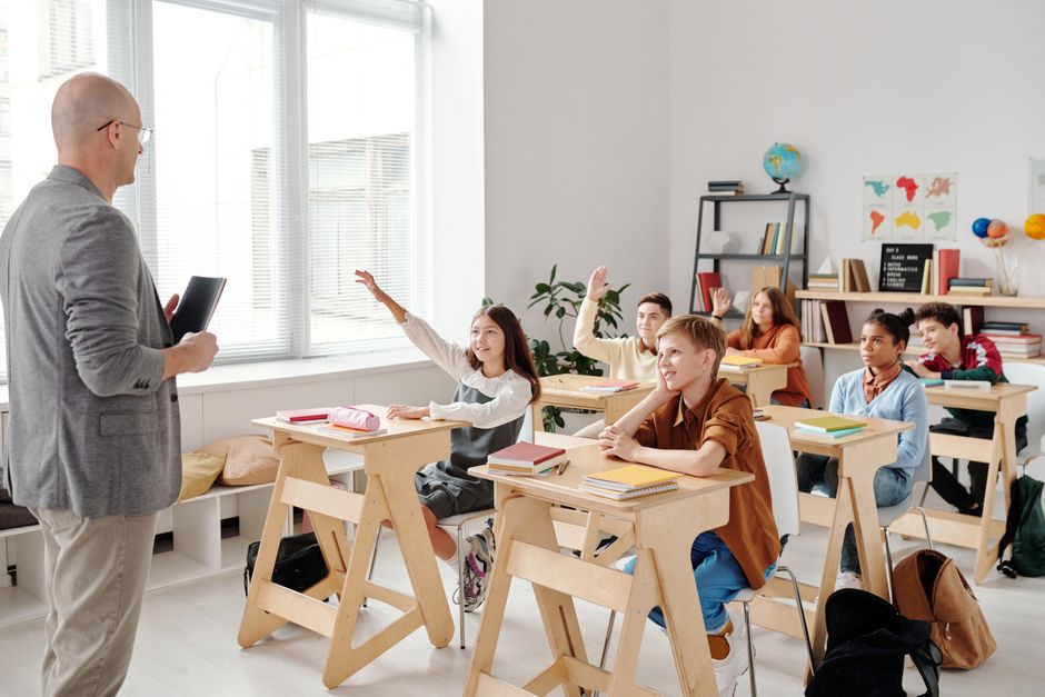 Students engage eagerly in a classroom, raising hands and participating in a lesson.