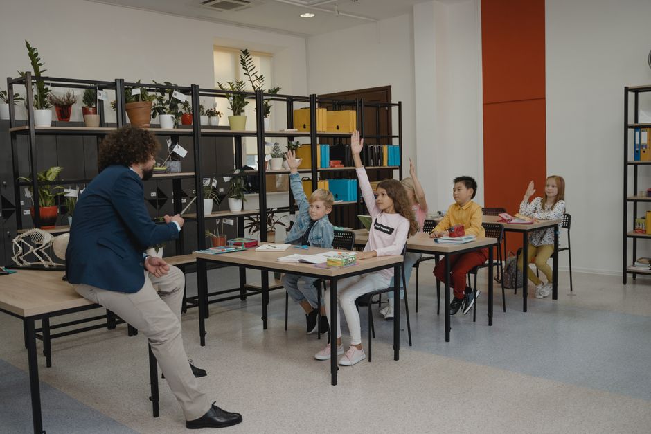 Students actively participating by raising hands in a modern classroom.